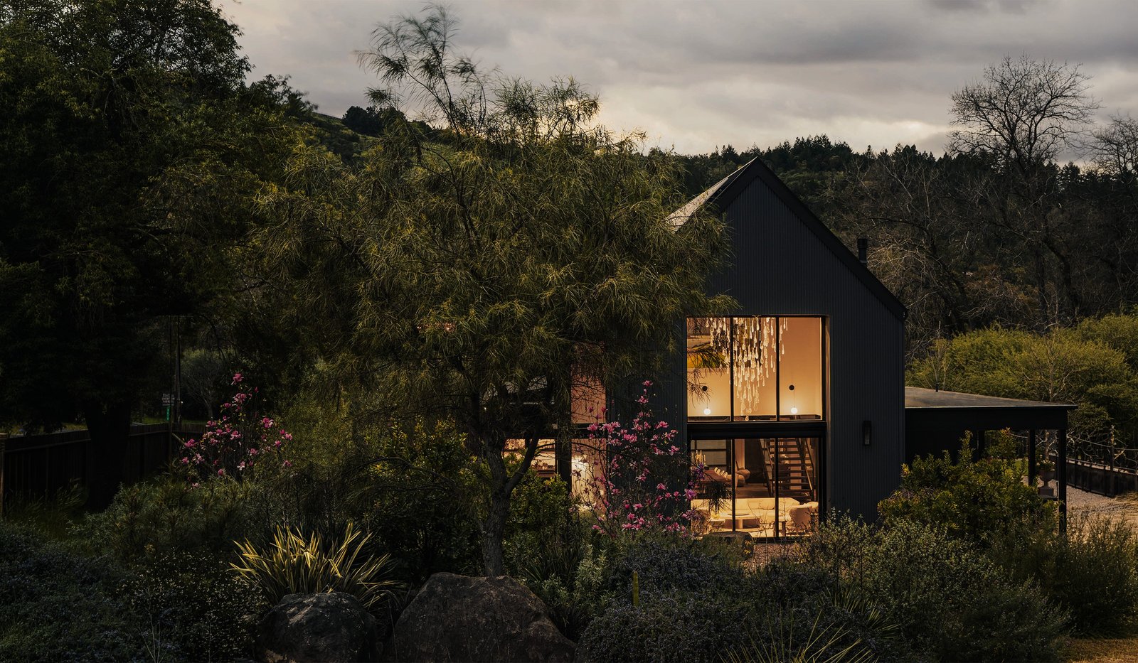 Contemporary residence illuminated at dusk within a considered natural landscape