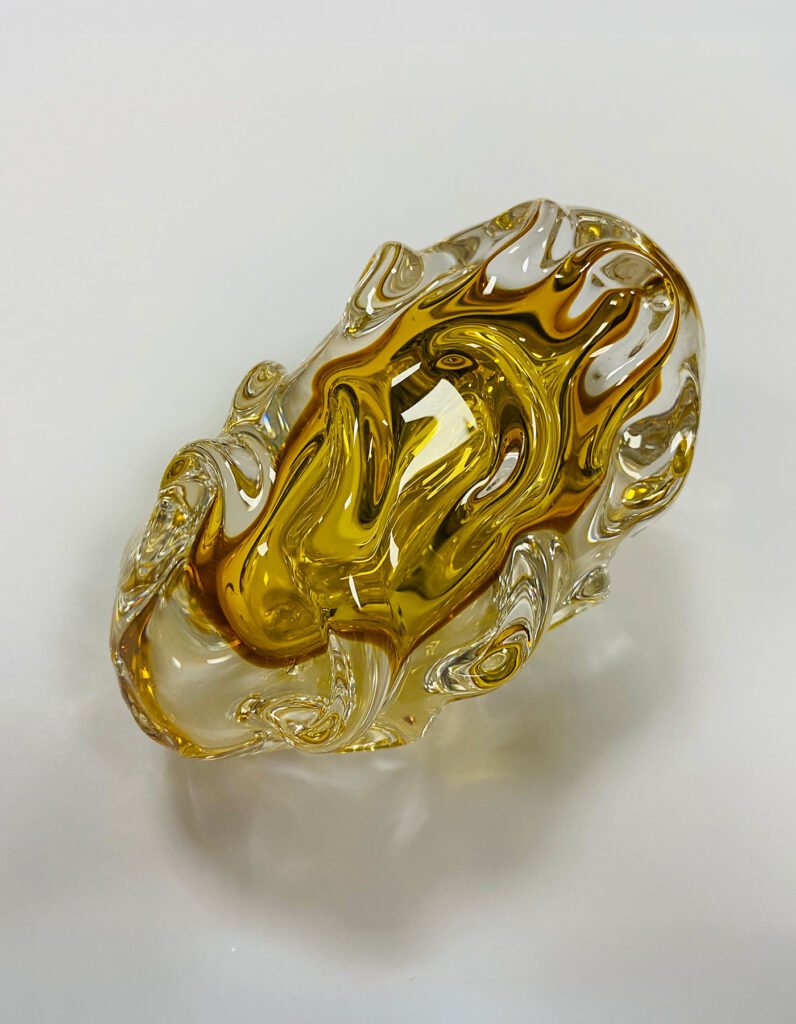Close-up of a hand-formed clear and amber glass lighting component