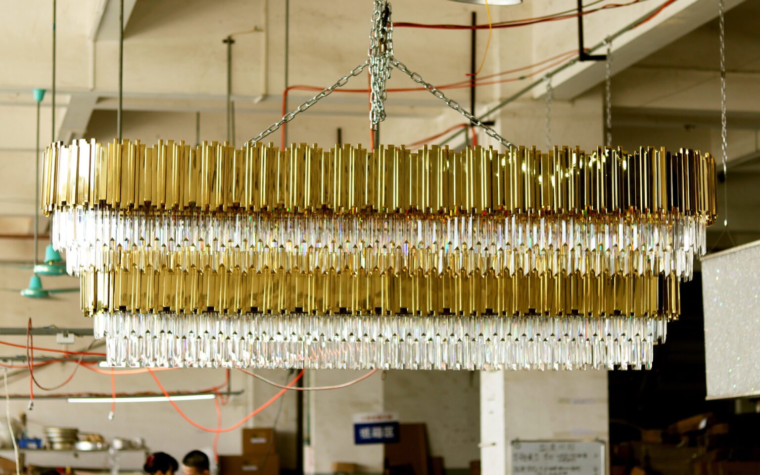 Large brass and crystal chandelier suspended for production review inside the lighting factory