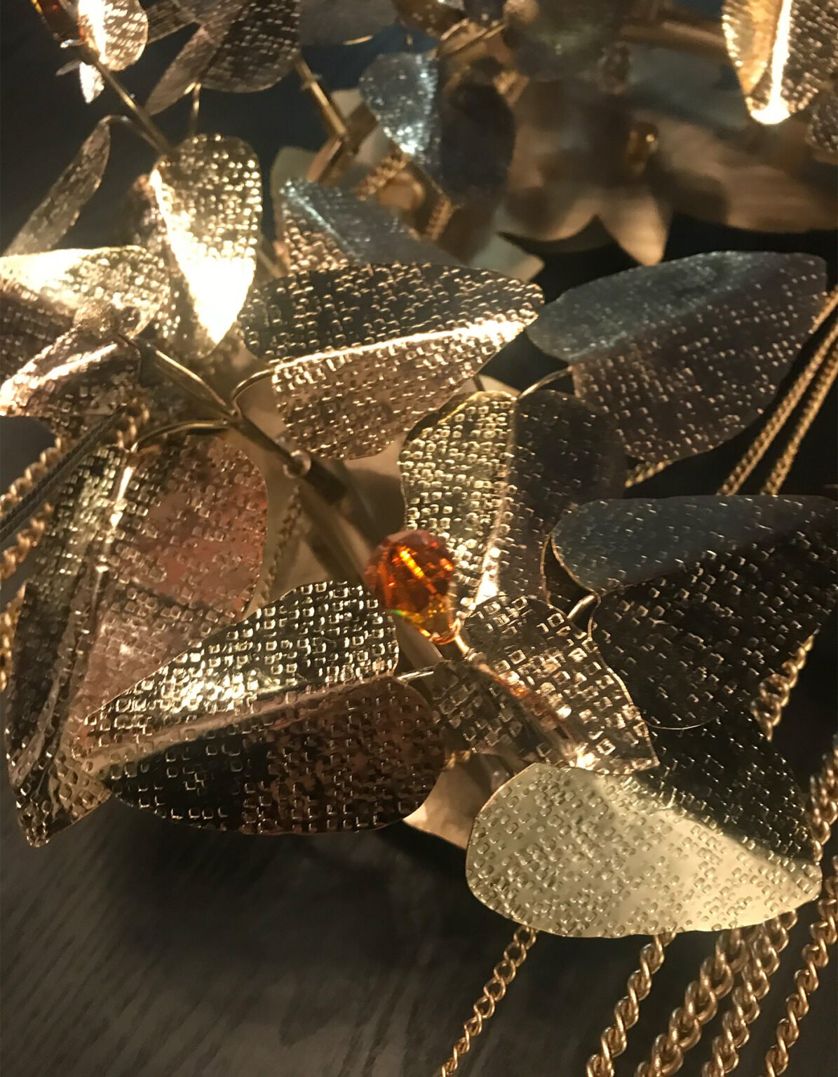 Close-up of sculpted metal leaves, textured surfaces and warm illuminated details
